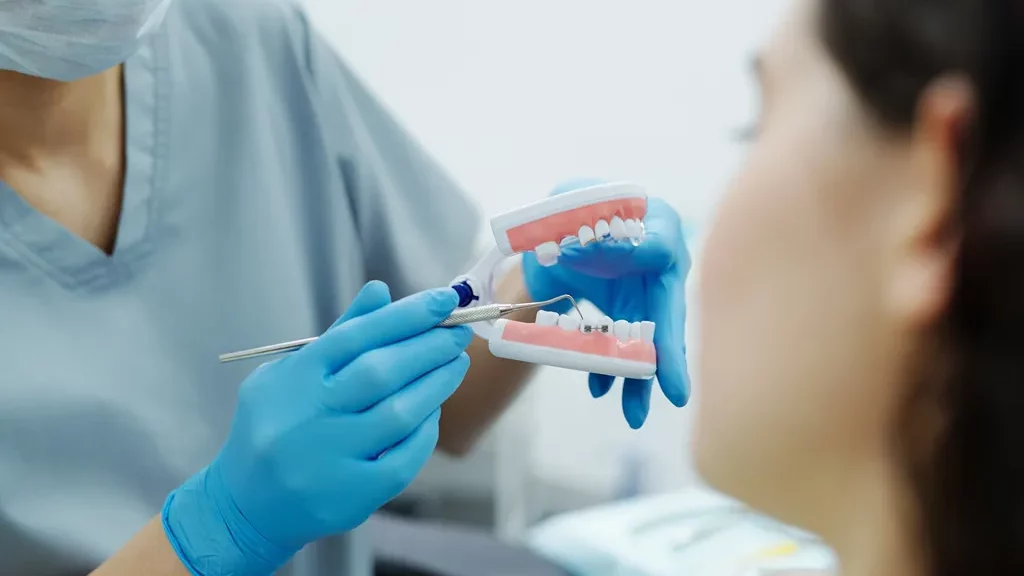 Dokter sedang menunjukkan cara sikat gigi behel yang benar